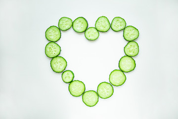 Cucumber slices are laid out in the shape of a heart, on a white background