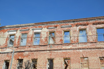 Fototapeta na wymiar Brick facade of an abandoned old building with windows.