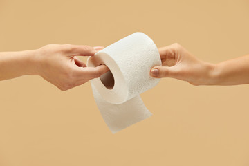 Toilet Paper. Roll In Caucasian Female Hand On Beige Background. One Woman Gives Tissue Paper To...