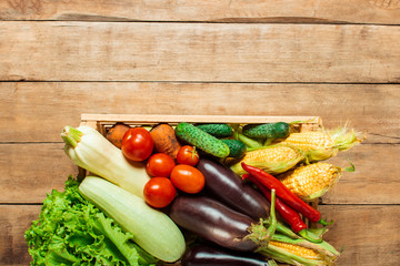 Wooden box with fresh vegetables on a wooden background. Good harvest concept, natural product. Flat lay, top view