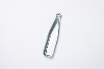 Bottle of clear crystal water on a white background under the sunlight. The concept of thirst, heat, summer, tropic. Flat lay, top view