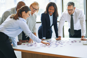 Smiling businesspeople solving a jigsaw puzzle in an office boar