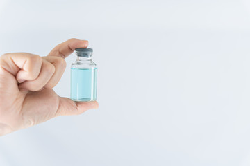Closeup hand of woman doctor or scientist wearing medical mask and holding medicine liquid vaccine vial bottle. COVID 19 or coronavirus concept.
