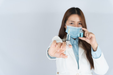 Closeup hand of woman doctor or scientist wearing medical mask and holding syringe and medicine liquid vaccine vial bottle. COVID 19 or coronavirus concept.