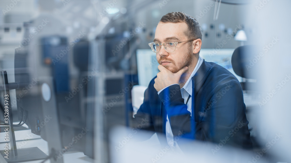 Aufkleber Shot of Thoughtful Industrial Engineer Working on a Personal Computer. He is Working in Cozy Office in Modern Factory with High-Tech Machinery.