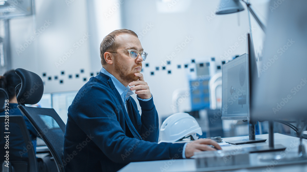 Poster Shot of Male Industrial Engineer Solving Problems, Working on a Personal Computer, He is Working in Office in Modern Factory with High-Tech Machinery.