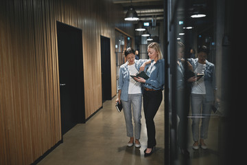 Two businesswomen talking together in the hallway of an office