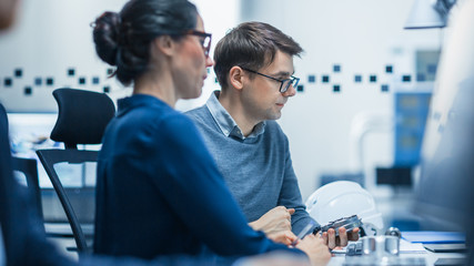 Modern Factory: Male Industrial Engineer Explains to Female Project Supervisor Functions of the...