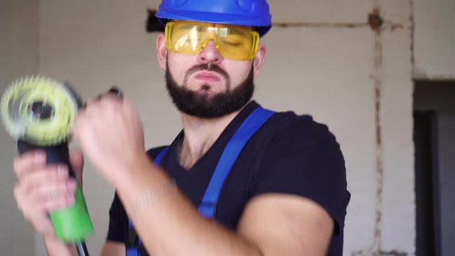 Young sexy male builder is dancing at a construction site. Portrait of a happy worker