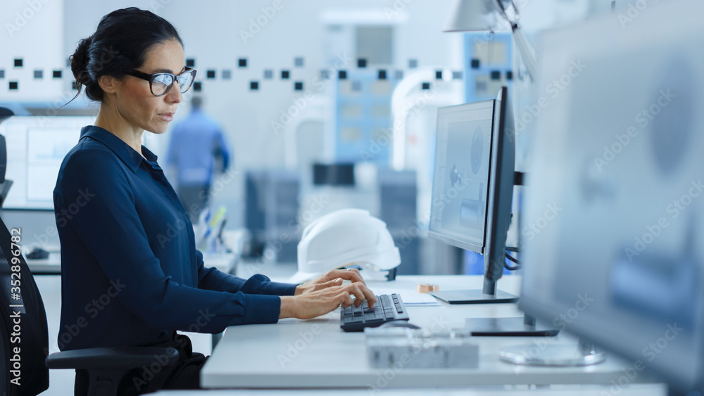 Poster Beautiful Female Engineer Working on Personal Computer in the High-Tech Industrial Factory, She Uses CAD Software to Model Heavy Industry High Tech Mechanism 3D Model. Side View Shot