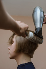 Fototapeta premium Young blonde girl doing hairdryer styling at home