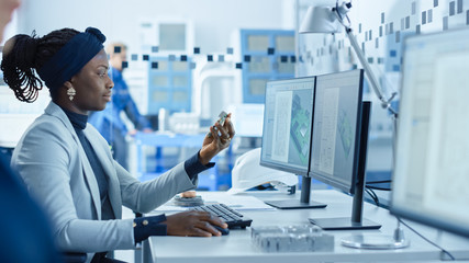 Electronics Factory: Female Electrical Engineer Holds PCB Prototype, Works on Computer, uses CAD...