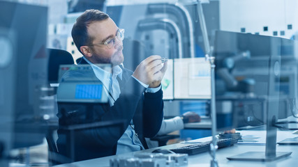 Electronics Factory: Male Electrical Engineer Holds PCB Prototype, Works on Personal Computer,...