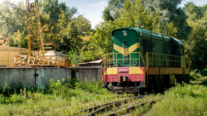 Fototapeta na wymiar Old diesel locomotive riding on railroad at old factory or construction site