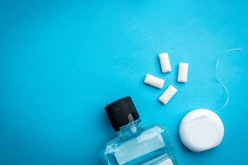 Oral rinse, gum and dental floss on blue background.