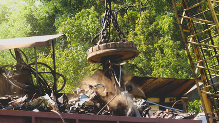 Image of industrial electric magnet lifting metal details and part on the junkyard
