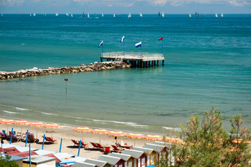Obraz premium Lido, Venezia. Regata domenicale di vele con spiaggia attrezzata e murazzo a mare.