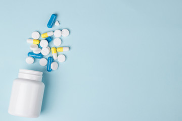 Assorted pharmaceutical medicine pills, tablets and capsules over blue background