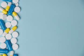 Assorted pharmaceutical medicine pills, tablets and capsules over blue background