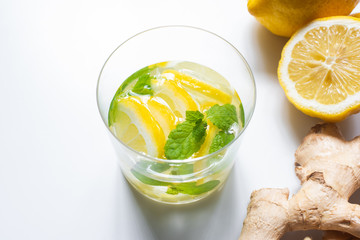 fresh lemonade in glass near lemon and ginger root on white background