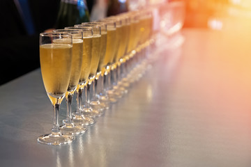 Row of glasses with sparkling wine, champagne or proseco close-up. Wine tasting, warm toned photo
