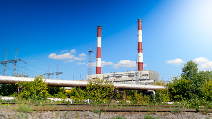 Fototapeta na wymiar Image of two red and white chimney on electric powerhouse against clear blue sky