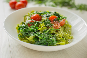 Close up Spinach Tagliatelle. Italian pasta with arugula, tomatoes and parmesan ready to eat.