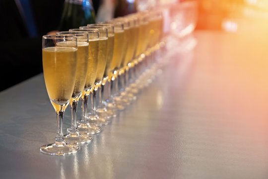 Row of glasses with sparkling wine, champagne or proseco close-up. Wine tasting, warm toned photo