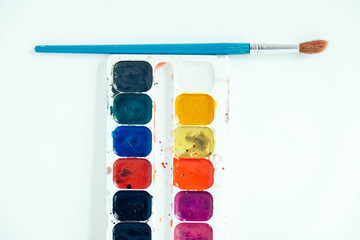 Set of watercolor paints and brush for painting on a white background. Top view. Copy, empty space...