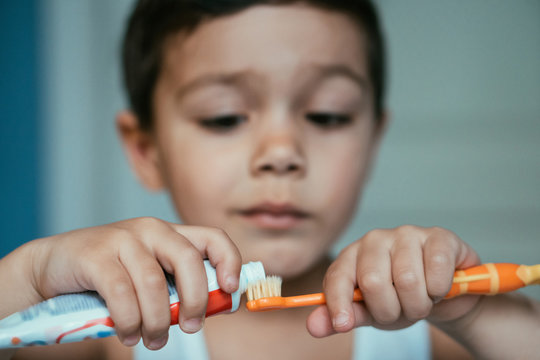 selective focus of diligent boy applying toothpaste on toothbrush