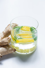 fresh lemonade in glass with lemon near ginger root on white background