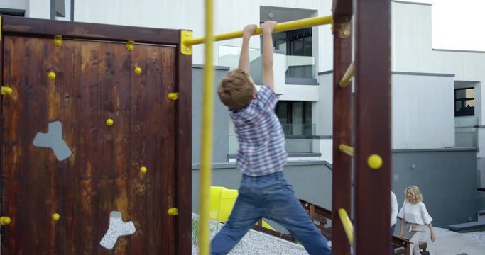 4K Of Boy Hanging On Monkey Bars And His Father Lifting Him Up