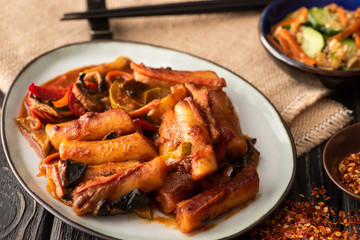 selective focus of spicy topokki near dried chili pepper on wooden surface