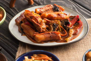 selective focus of spicy topokki on plate and wooden surface