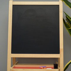 Fototapeta na wymiar Empty black board with green plant on the gray background. Copyspace