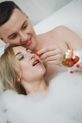 Obraz na płótnie Canvas Loving couple in a bath with strawberries.