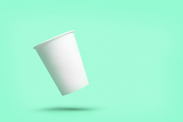 White paper cup of coffee colored background.  Flying paper cup on violet background. Isolated for mock up