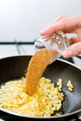 Someone&acute;s hand adding the brown sugar to he pan with chopped apple