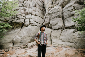 Portrait of a young bearded man in a hat in the mountains