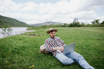 Obraz premium Man freelancer working on laptop in the mountains, remote work concept