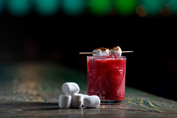 красный ягодный алкогольный коктейль в прозрачном стакане  с зефиринками 