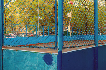 Blue iron fence on the background of a blurred empty playground. Basketball ring. Quarantine, pandemic, self-isolation.