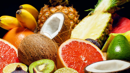 Closeup photo cut of kiwi, pineapple, orange, grapefruit, banana, coconut, avocado and lime. Exotic tropical fruits