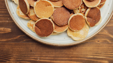 Freshly baked a plate of poffertjes, traditional Dutch Mini Pancakes without any other ingredients with the wooden background