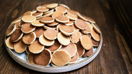 Freshly baked a plate of poffertjes, traditional Dutch Mini Pancakes without any other ingredients with the wooden background