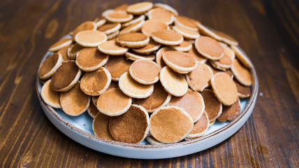 Freshly baked a plate of poffertjes, traditional Dutch Mini Pancakes without any other ingredients with the wooden background