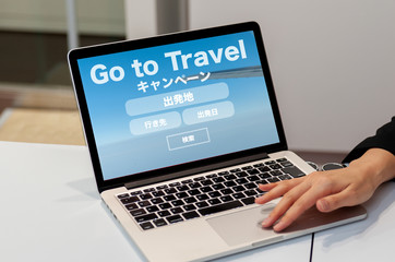 航空券のオンライン予約検索のイメージ　ノートパソコンでフライト予約検索の画面を見せている女性の手　go toトラベル