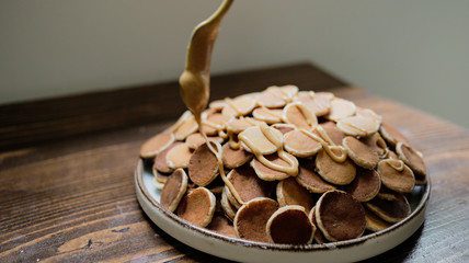 A plate of Dutch Mini Pancakes, poffertjes with peanut butter on the wooden background