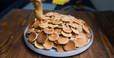A plate of Dutch Mini Pancakes, poffertjes with peanut butter on the wooden background