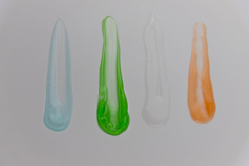 Different colors of antiseptic alcohol gel, spread with a finger on white background, coronavirus prevention